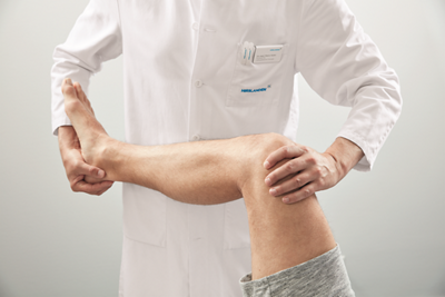 Arzt untersucht Patient am Knie